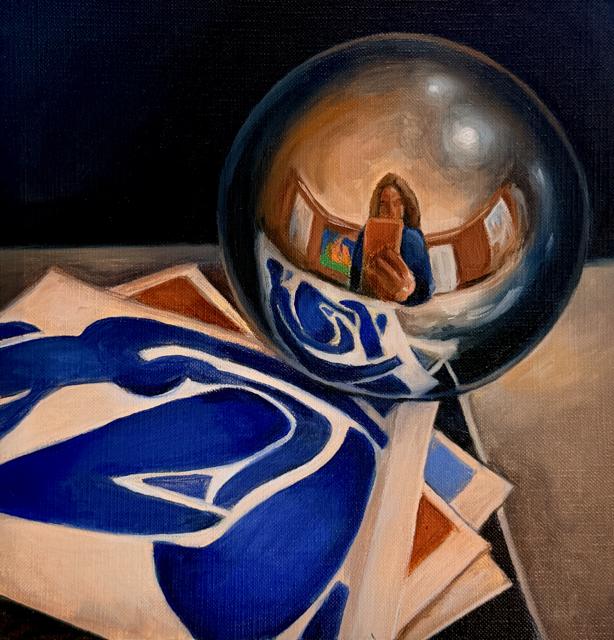 A mirrored glass sphere reflecting the artist, resting on an abstract blue and white print