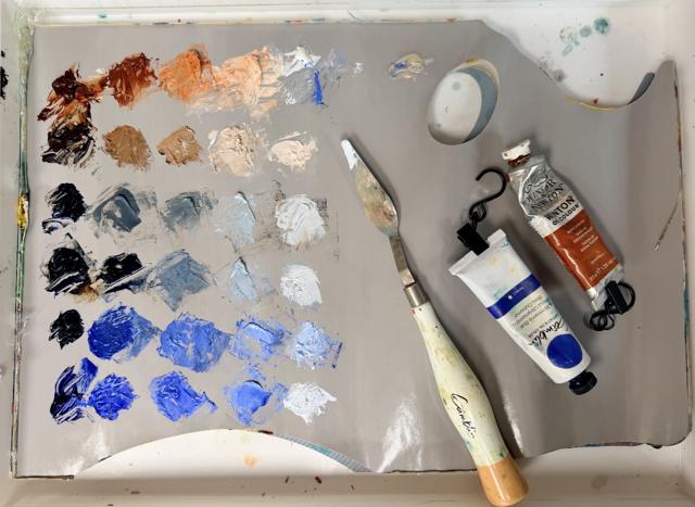 Paint palette with mixed colors, brushes, and paint tubes