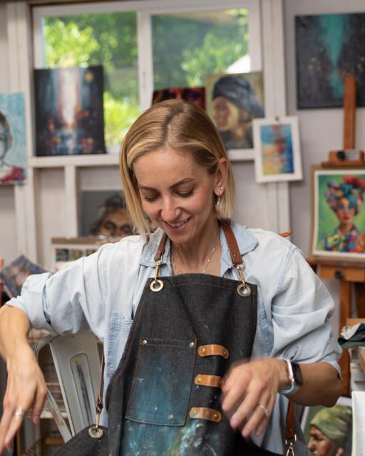 Color photo: smiling while mixing paint in the studio